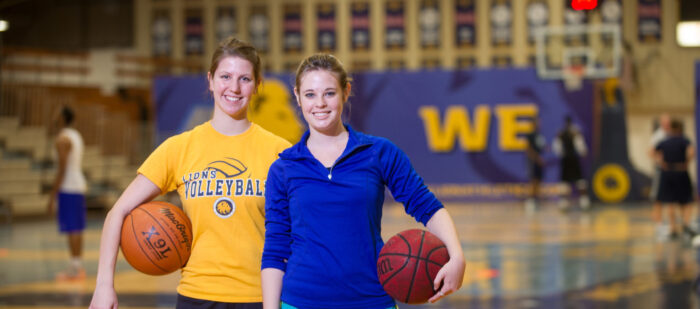 Two female athletes holding basketballs.