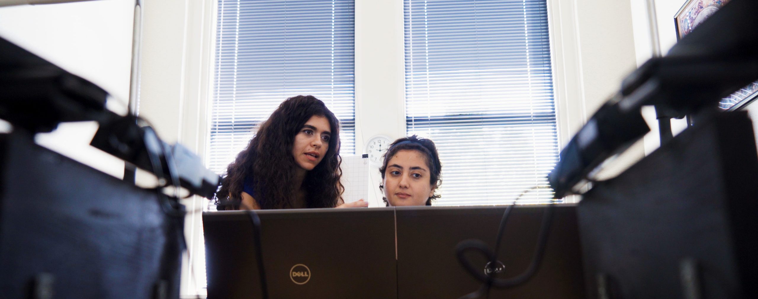 Two females, one is teaching the other about something on the computer.