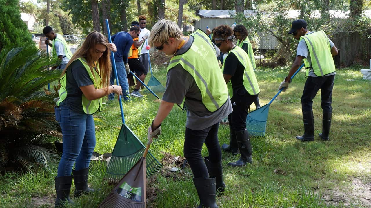 A group of students racking leaves.