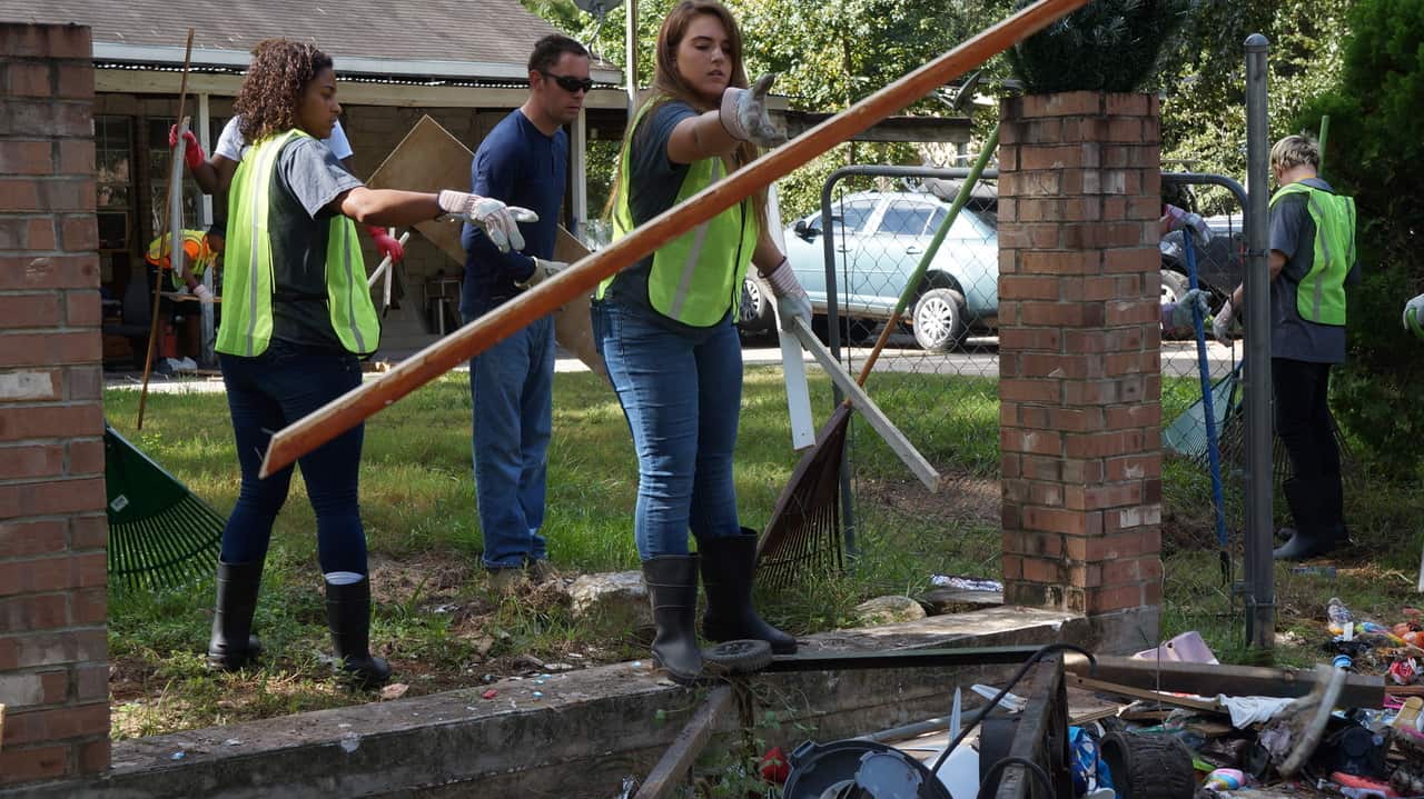 Individuals placing wood in a pile of things.