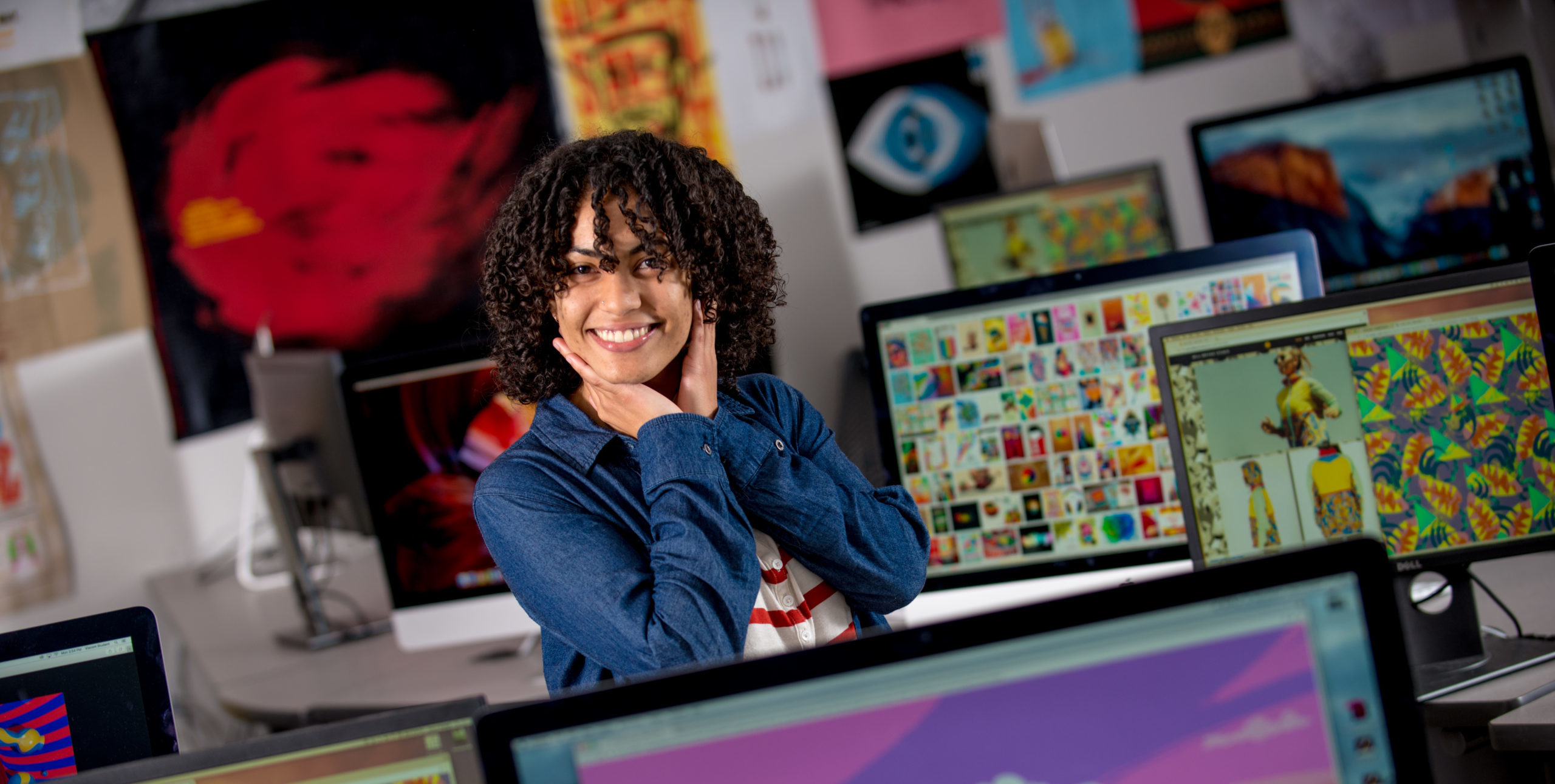 Student smiling around many computers.