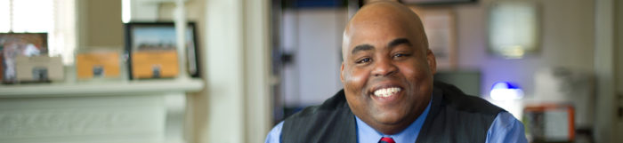 man sitting at desk with smile