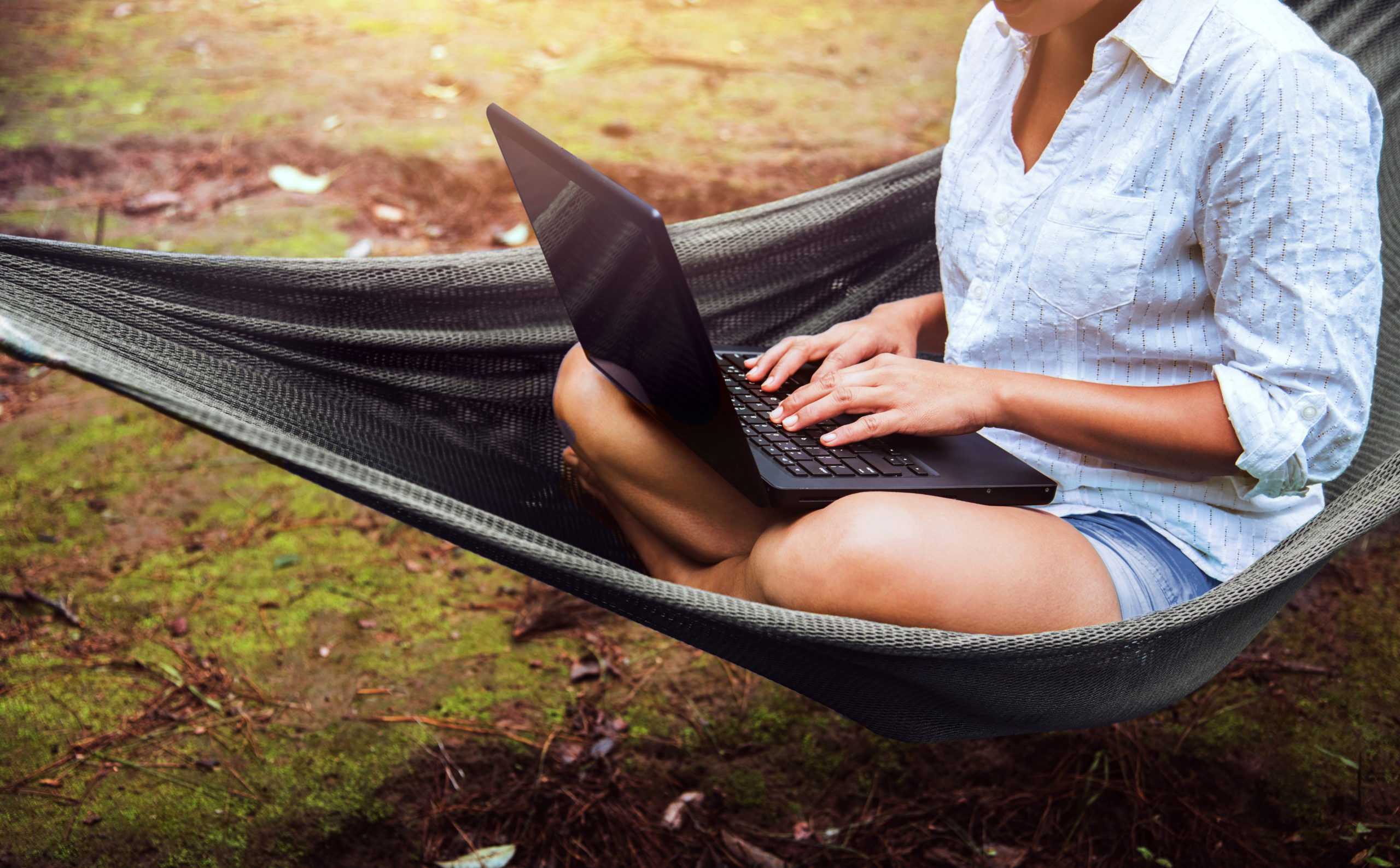 Woman reading outside on a laptop.