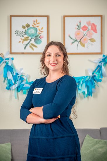 A woman stands with her arms folded in front of her.