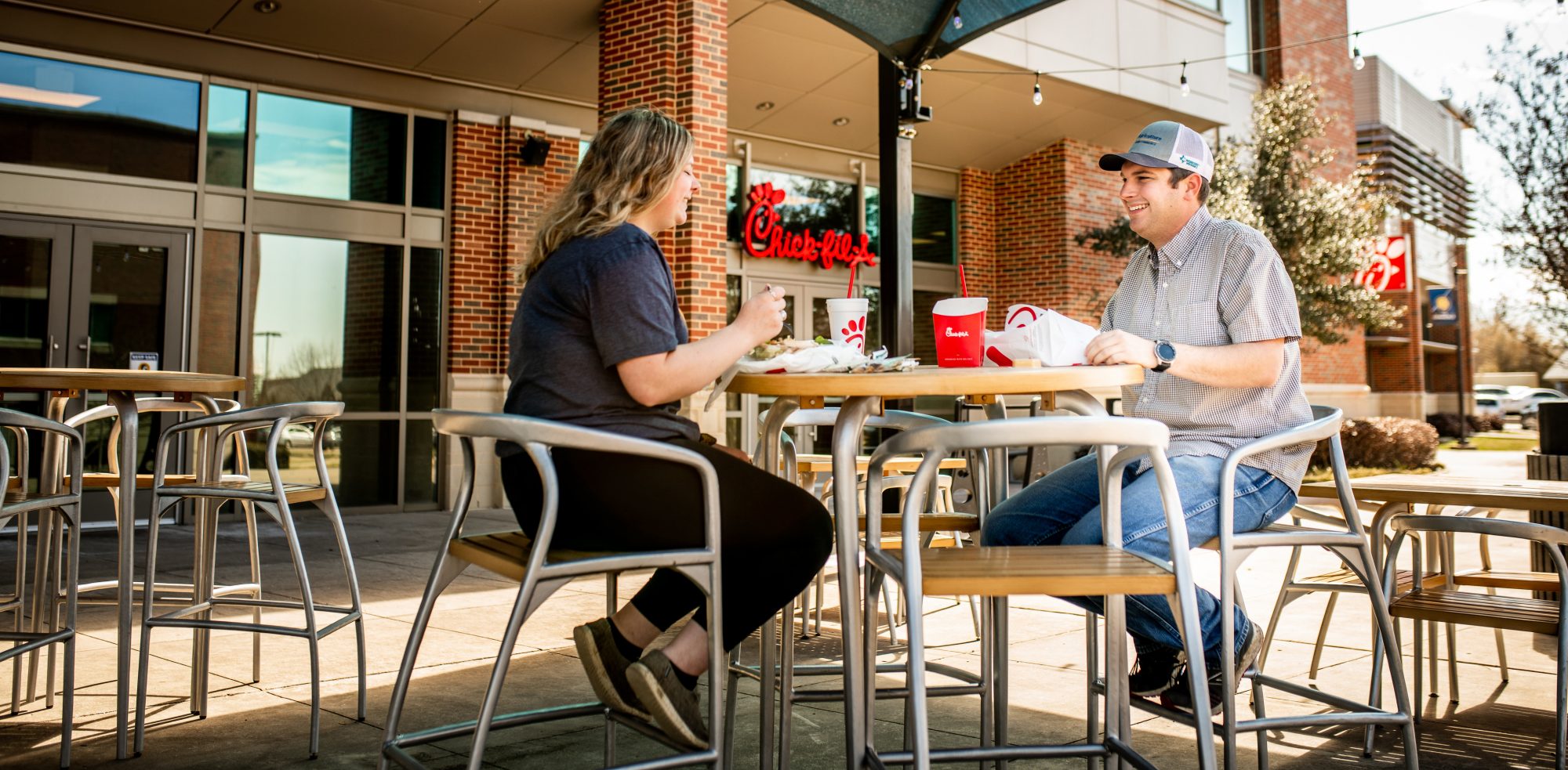 Two people eating outside in front of Chick-fil-a.