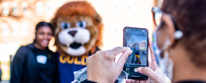 A female student having her picture taken with Leo the Lion.