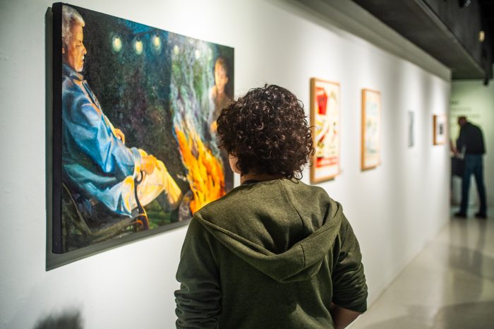 A male student looking at a painting in a art gallery.