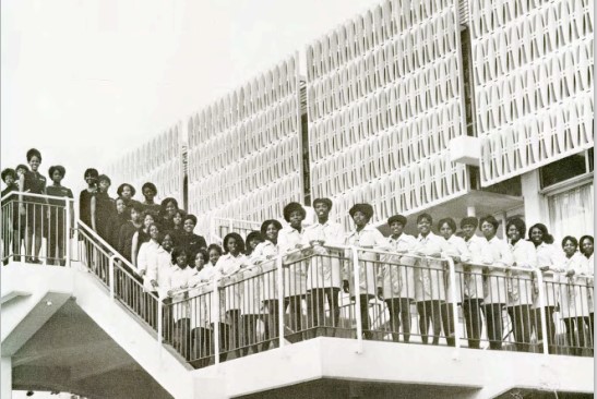 A group of African American females smiling for a picture in front of a building.