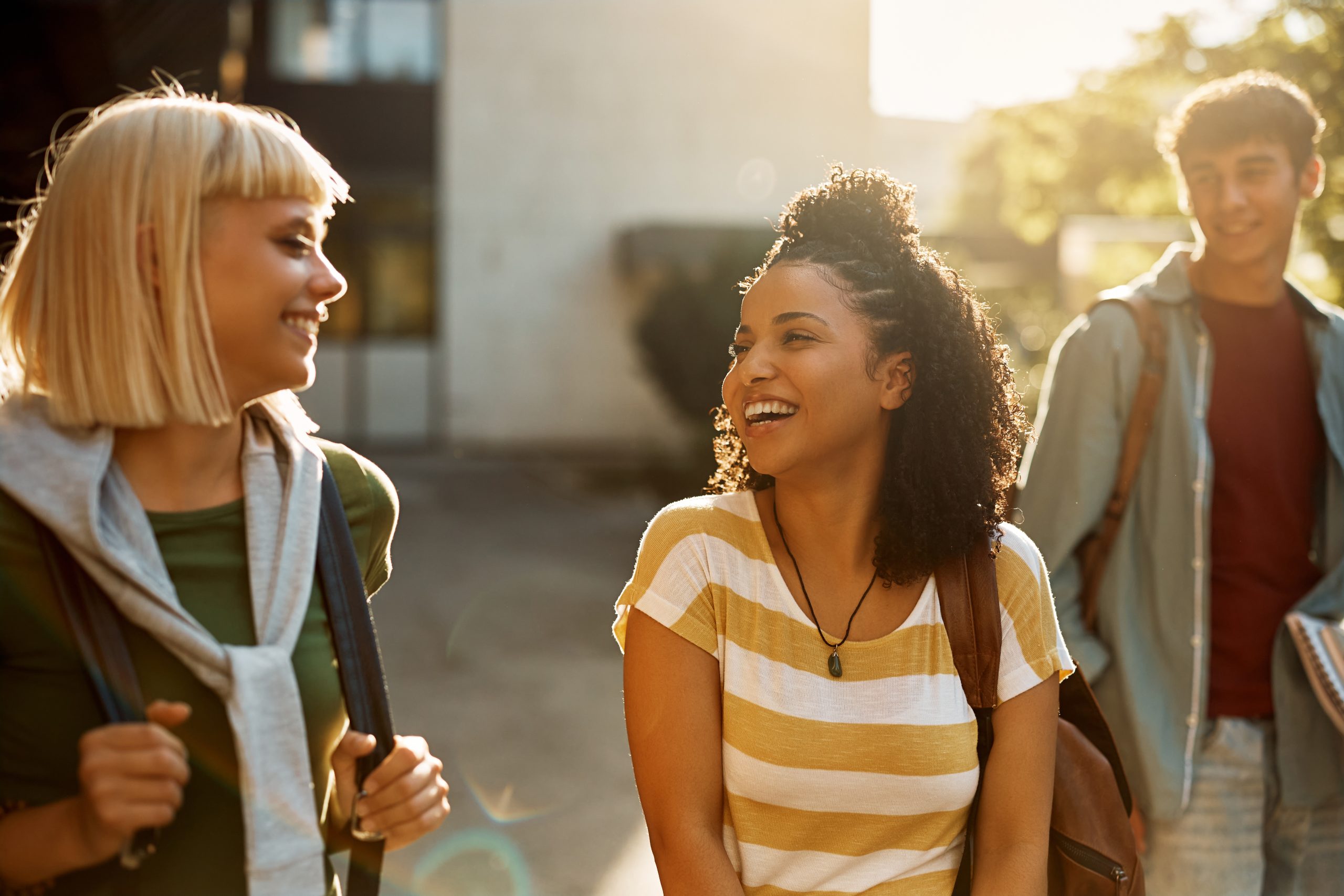 Multiracial group of cheerful students talk while walking through campus.