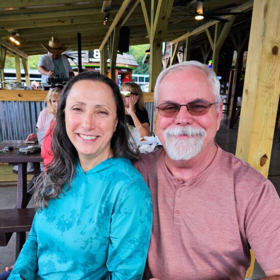 Two people posing for a photo in an outdoor restaurant.