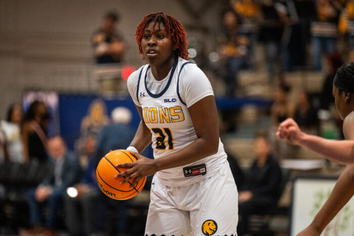 A female basketball player wearing a Texas A&M-Commerce Lions jersey, number 31, focuses while holding an orange basketball, preparing for a play during a game.