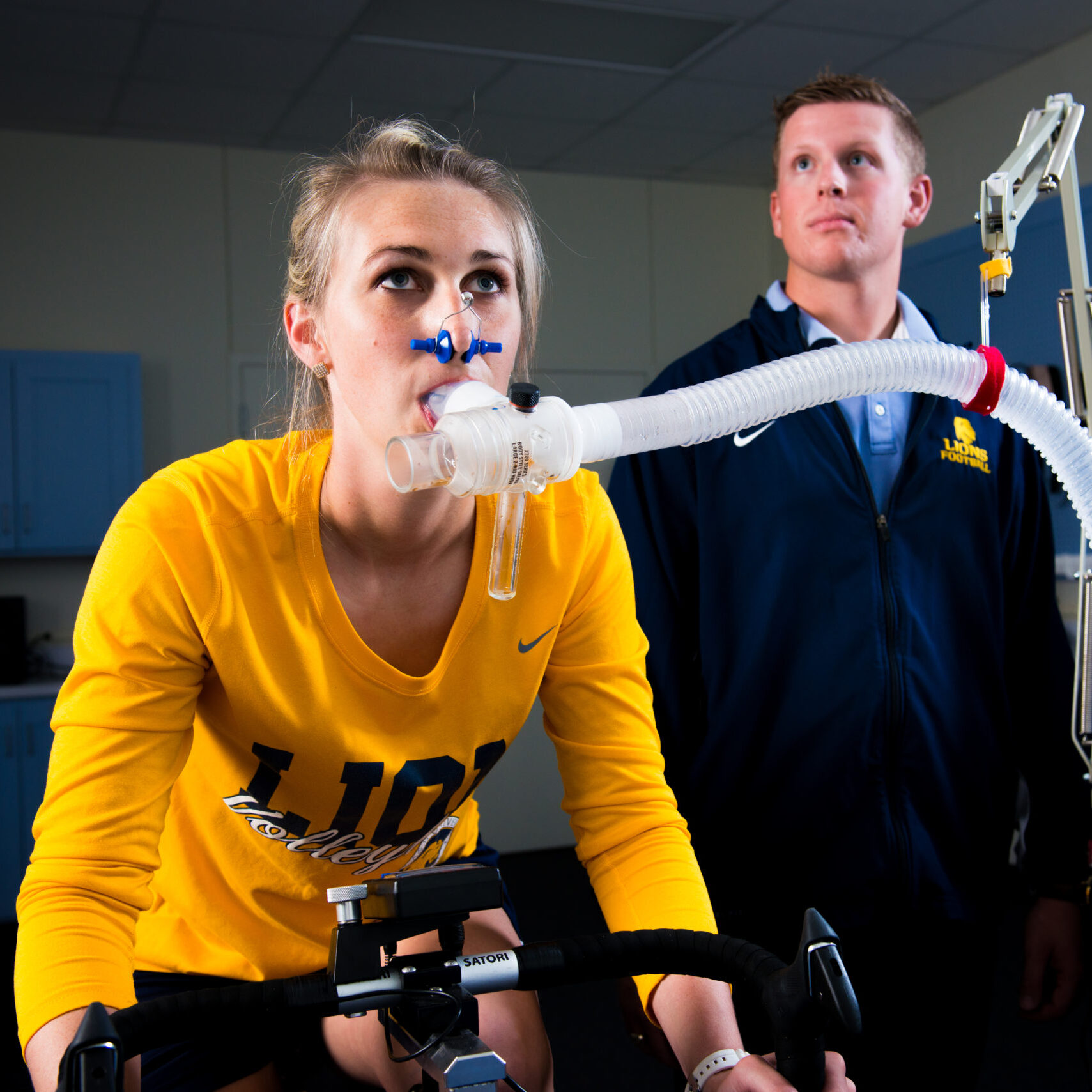 Young lady on exercise bike with ventilator tube measuring oxygen levels.