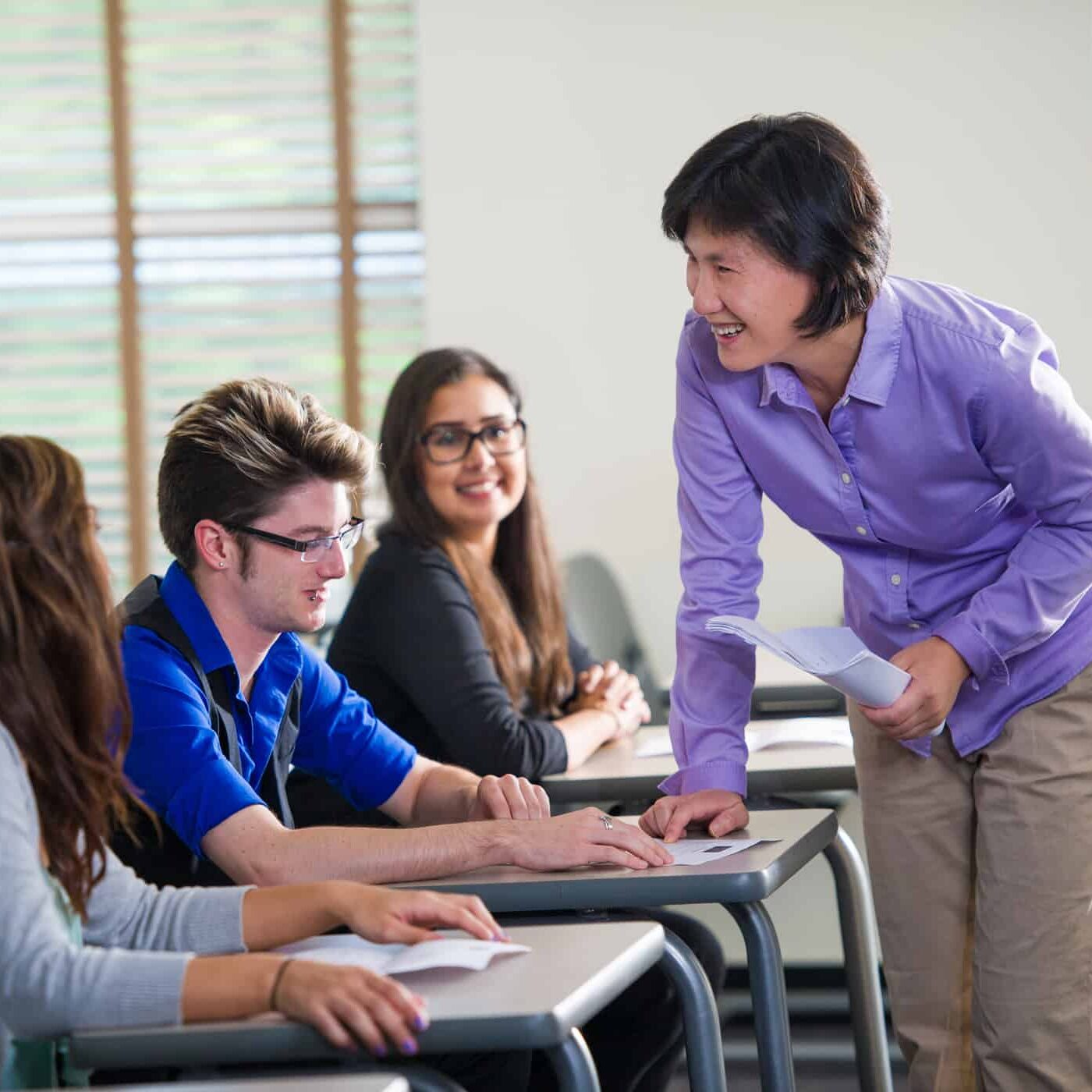A professor interacting with students in a classroom.
