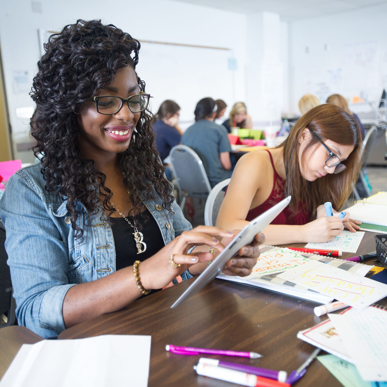 A female student using a tablet for an assignment she is completing with a colleague.
