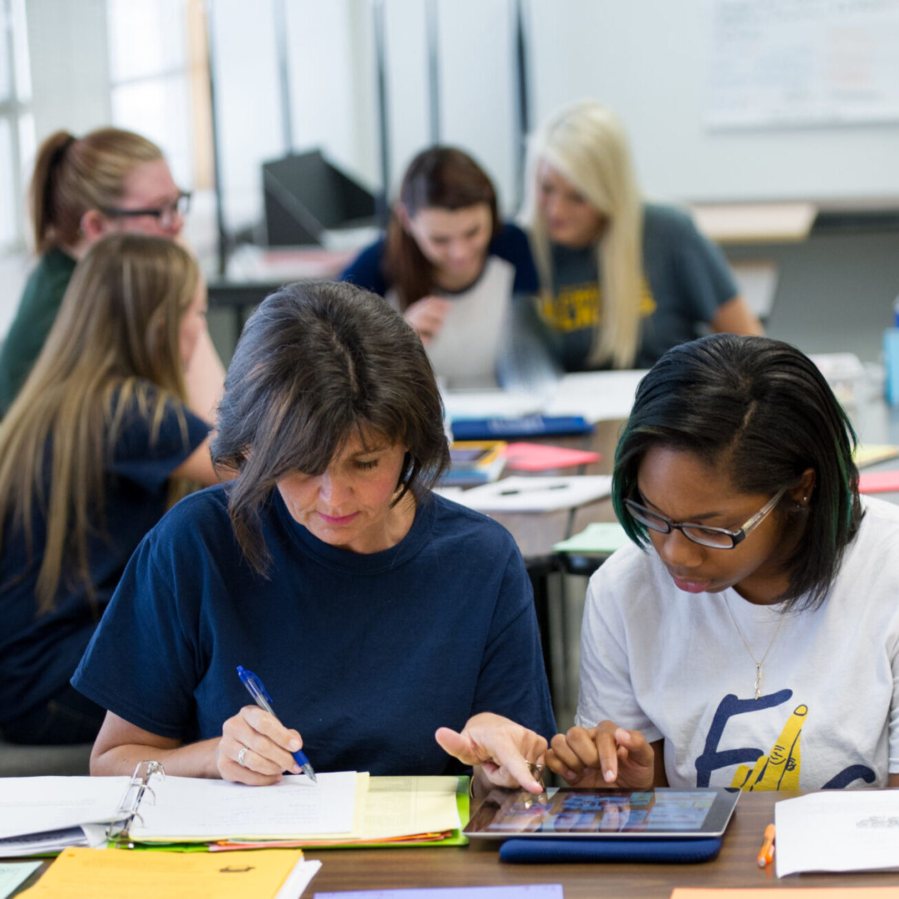 Two students working together while using a digital tablet.