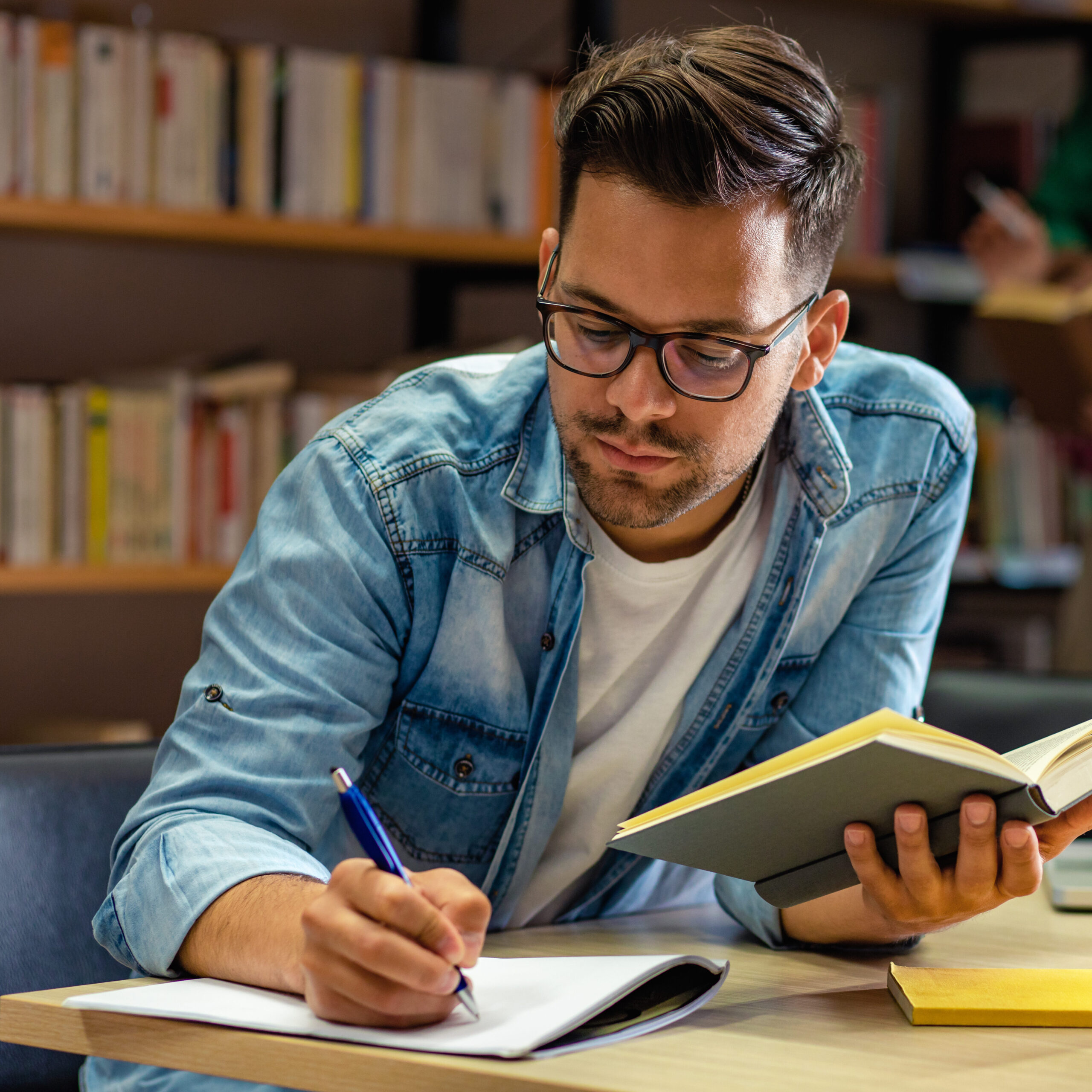 Young male student study in the library reading book.