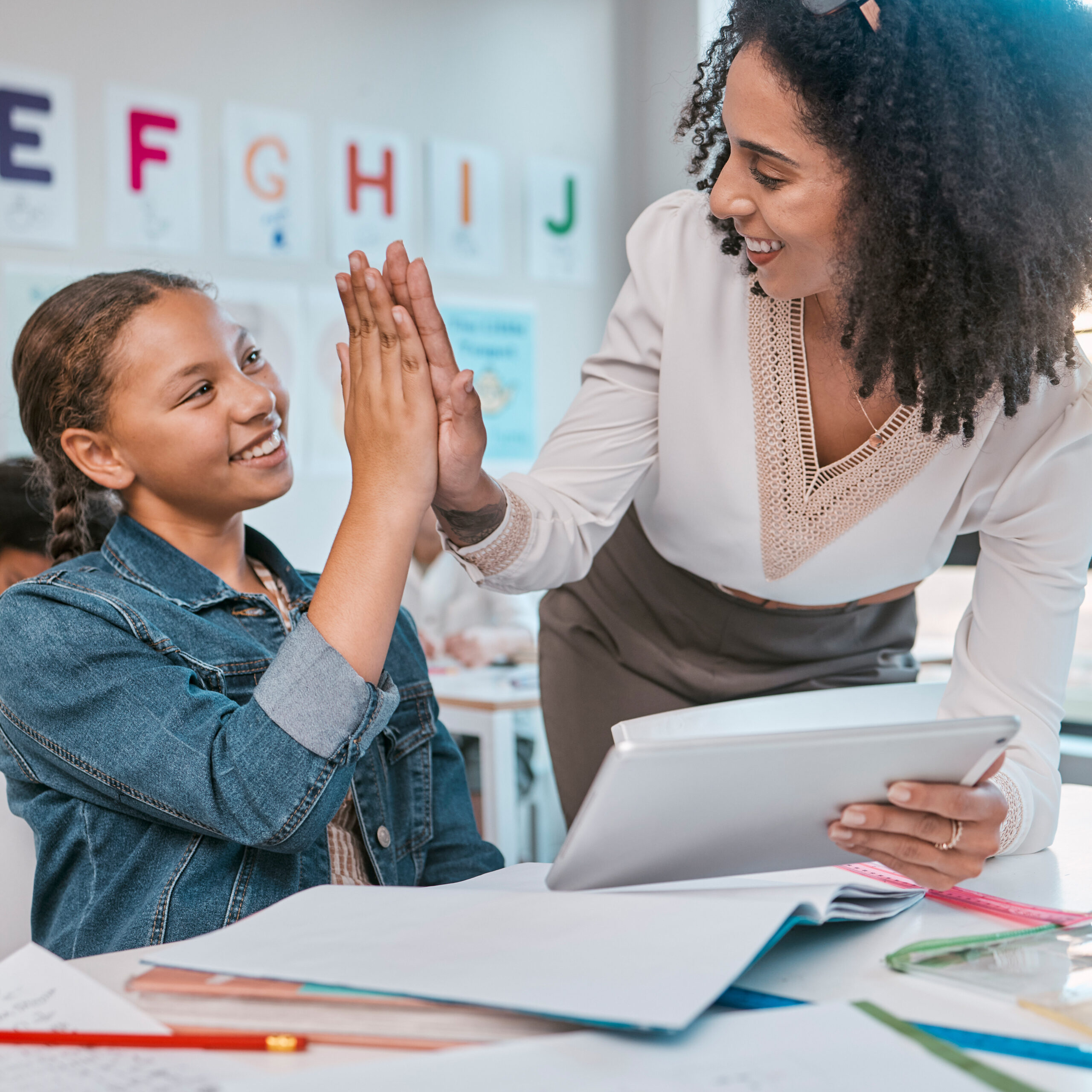 Tablet, high five and teacher with child education, learning and support, achievement and classroom goal. Mentor, black woman or person and girl in success hand sign for English, language development.