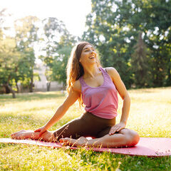 Young slim woman doing stretching or yoga relaxing exercise at public park. Lifestyle and Meditation concept.