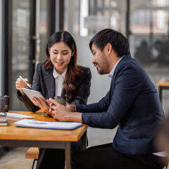 Team of confident Asian business people point to graphs and charts to analyze market data, balance sheet, account, net profit to plan new sales strategies to increase production capacity.