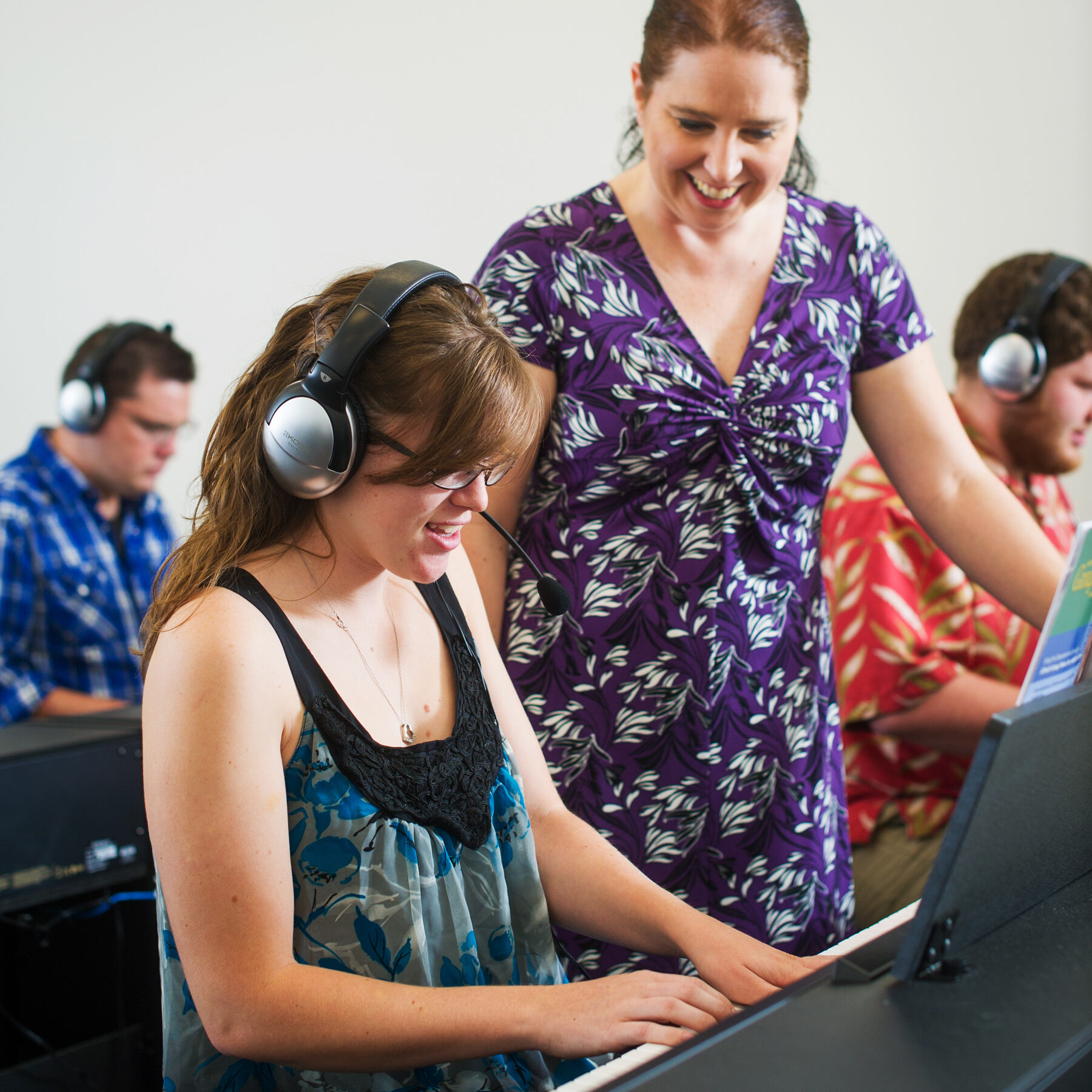 student playing keyboard with instructor observing with smile
