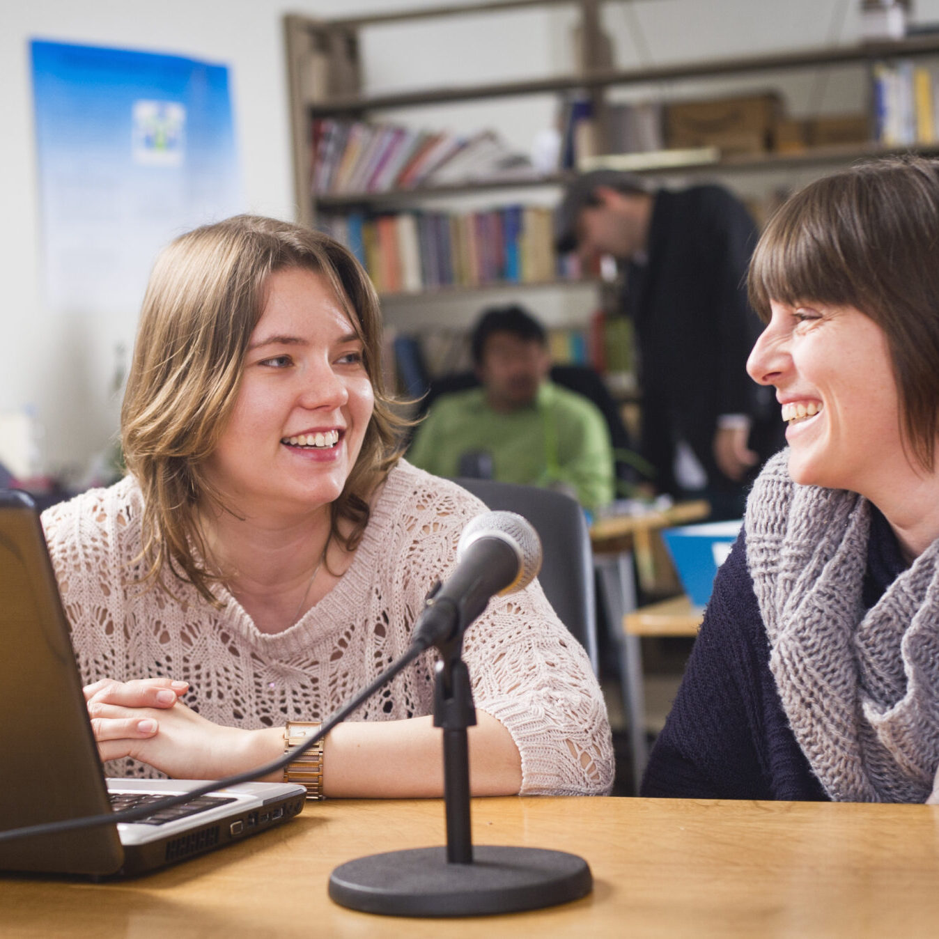 Professor sitting down with student with in front a laptop and a microphone.