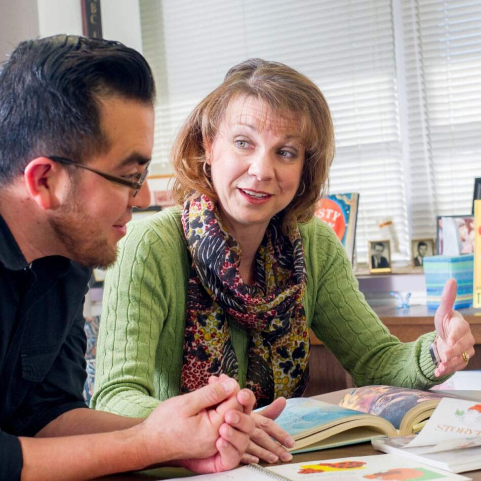 Two professor explaining study material to a male student.