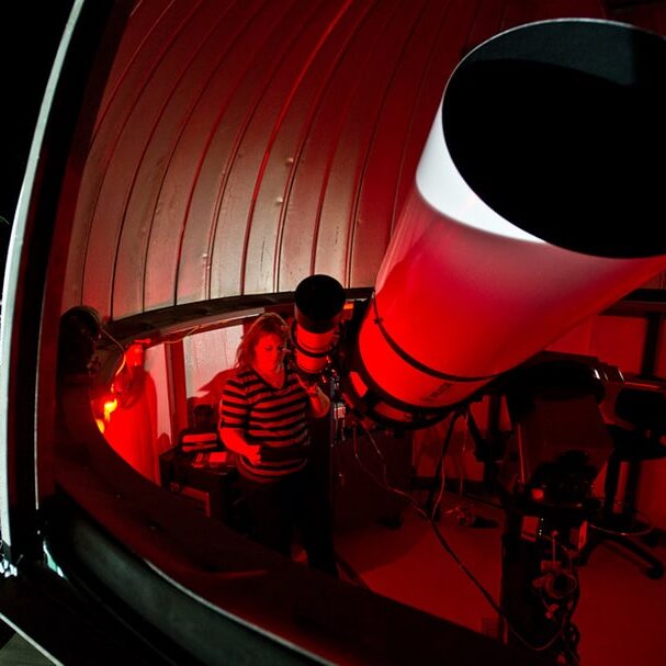 Students viewing stars with giant telescope.
