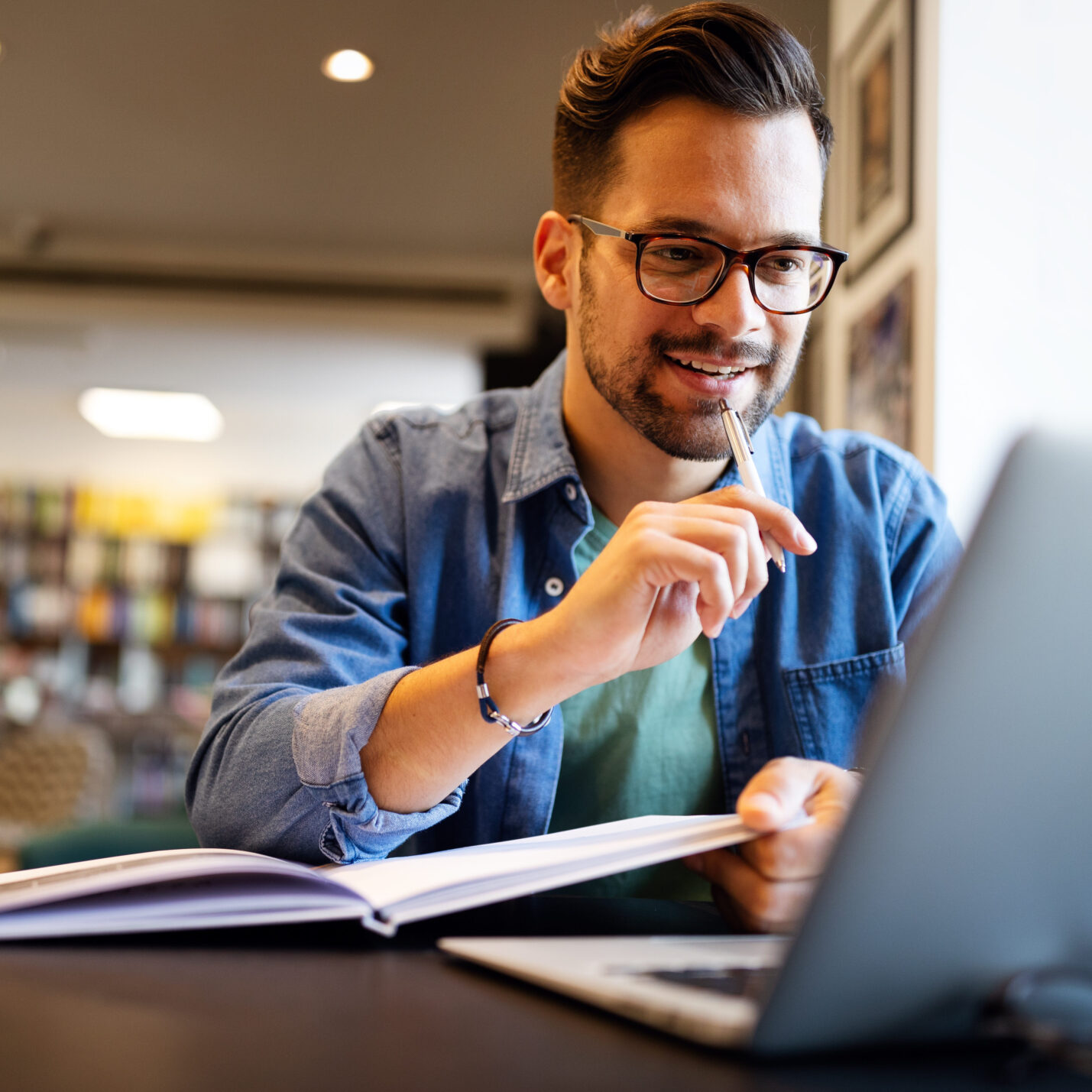 Smiling male student working and learning in a library