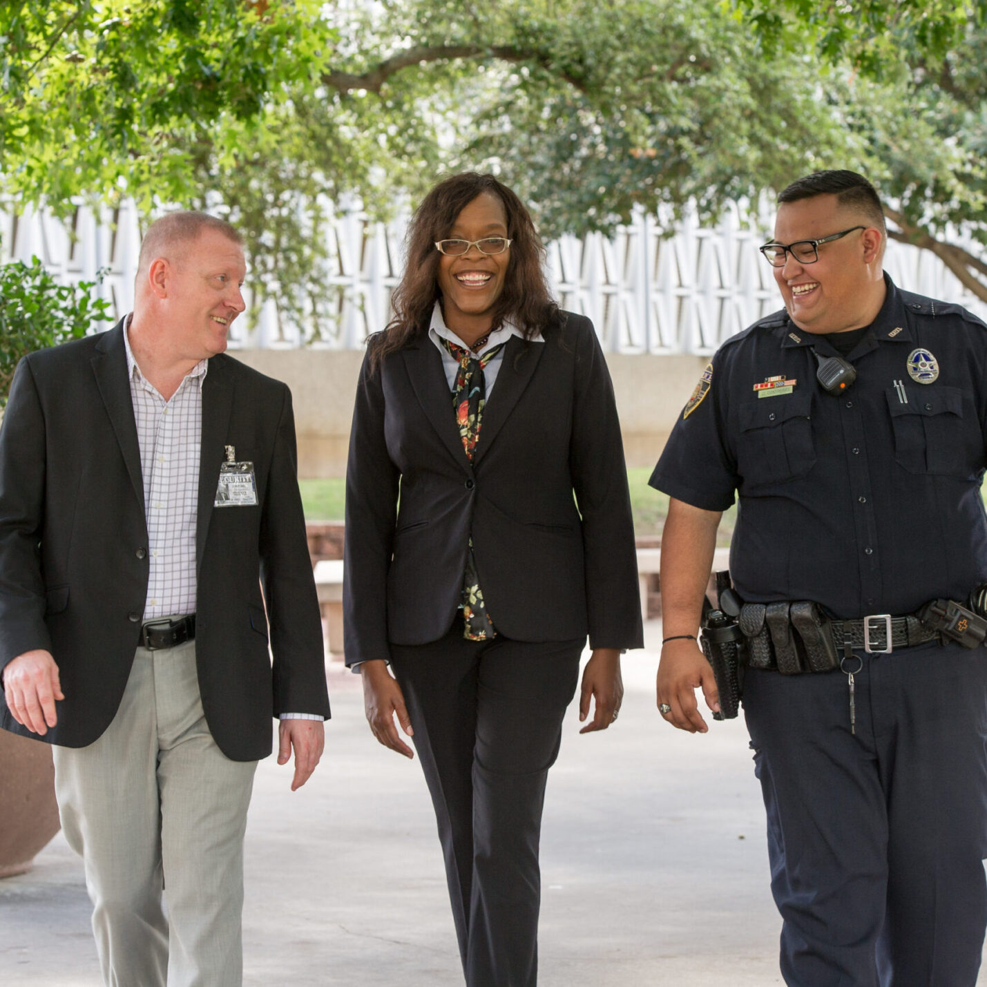 Three professionals walking, smiling, and talking to each other.