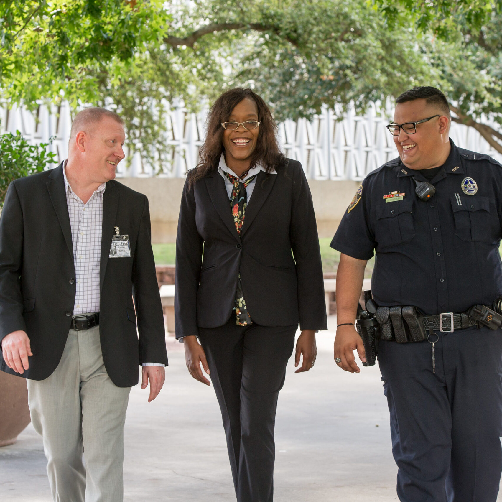 Three professionals walking, smiling, and talking to each other.