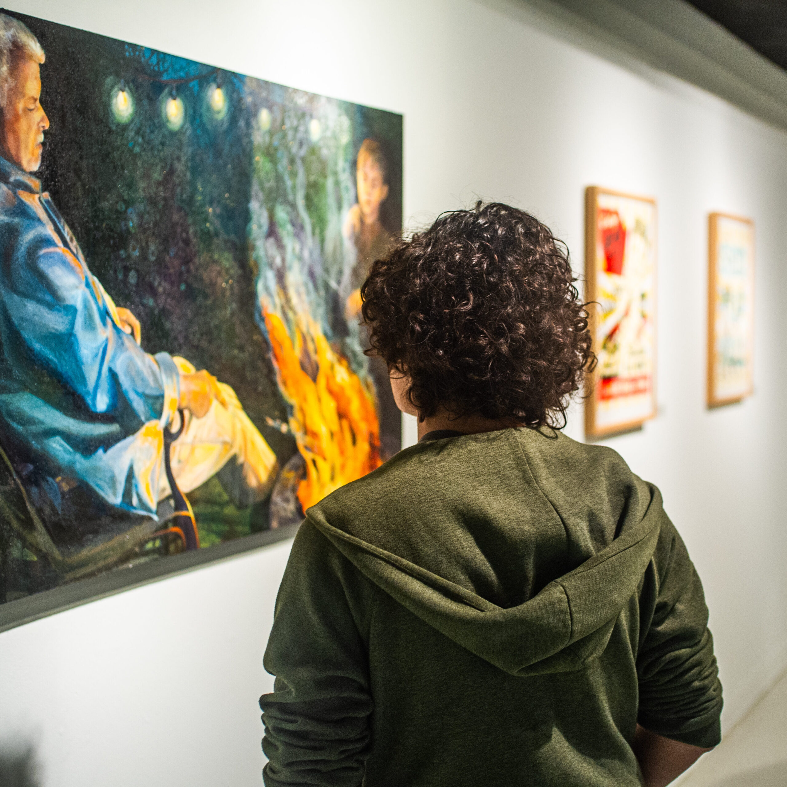 A male student looking at a painting in a art gallery.