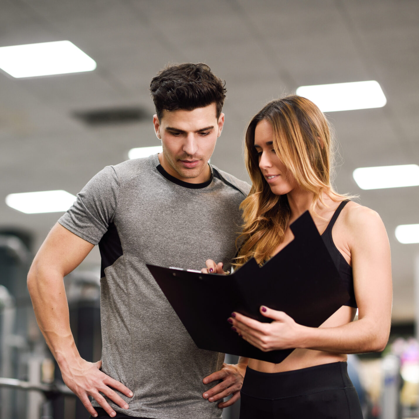 Personal trainer and client looking at his progress at the gym. 