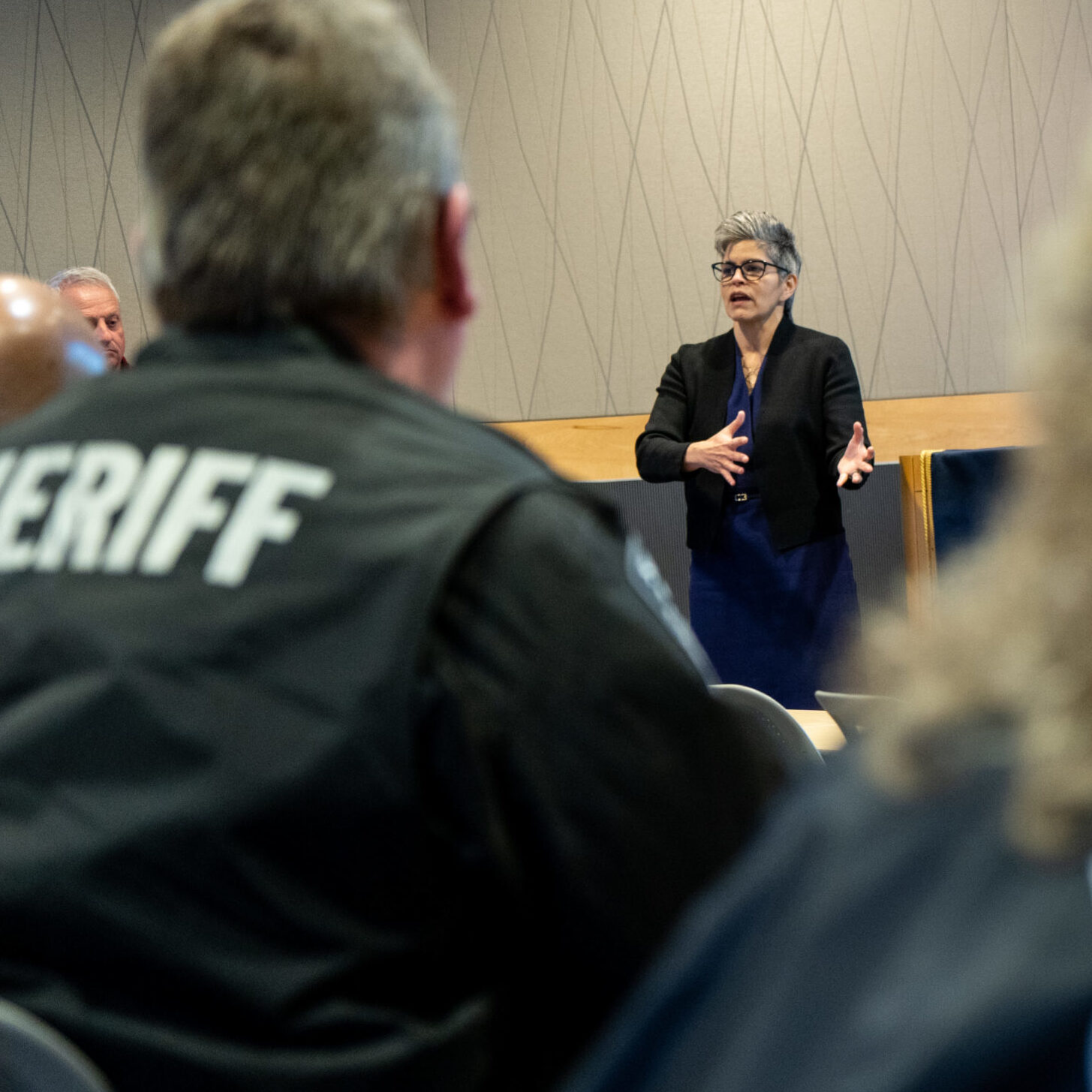 Faculty member instructing class with two class mates wearing sheriff uniform jackets.