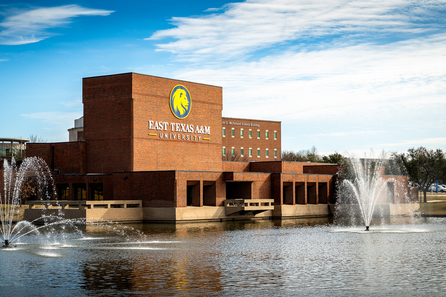 Performing Arts Center of East Texas A&M University with fountains and a clear blue sky.