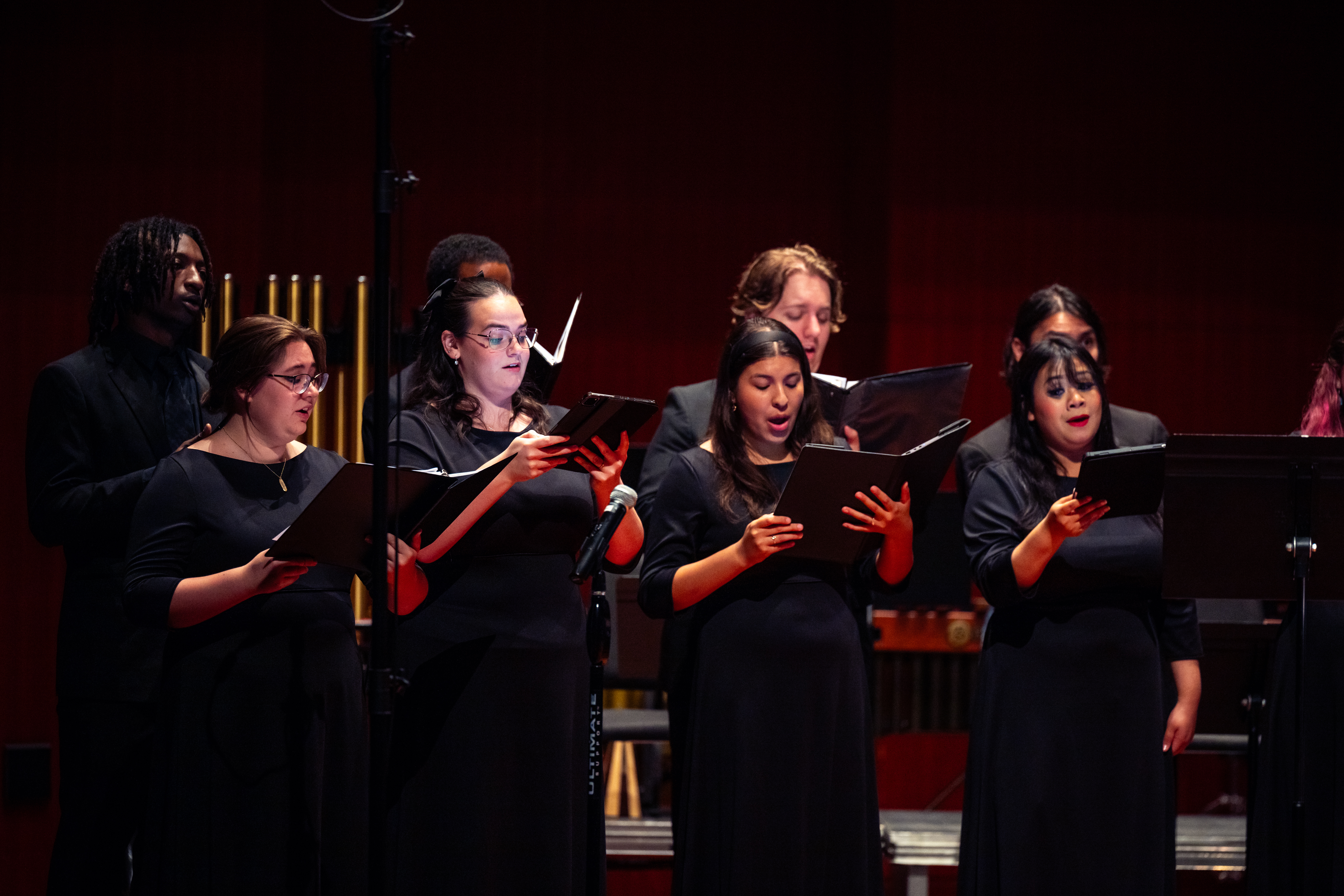 Members of a choir singing on stage during a concert. The singers are university students.