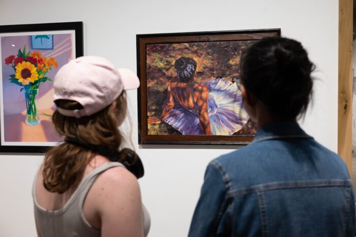 Two people observe a painting in an art exhibition.