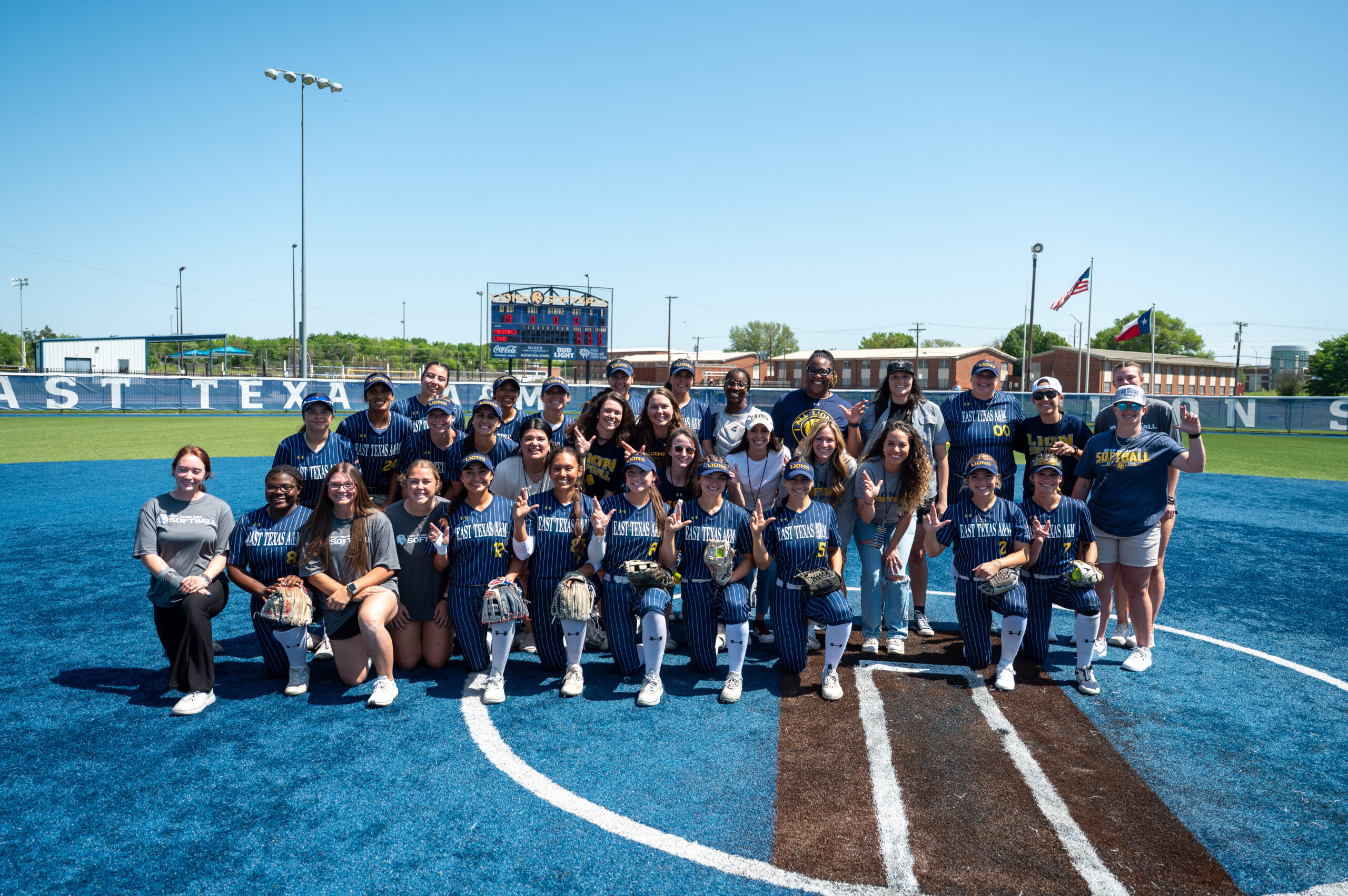 A college softball team poses on the field for a team photo.