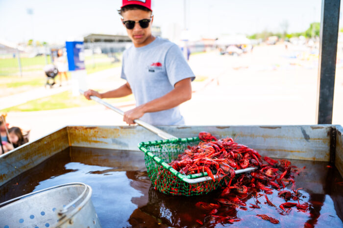 A man pulling cooked crawfish out of a big pot.