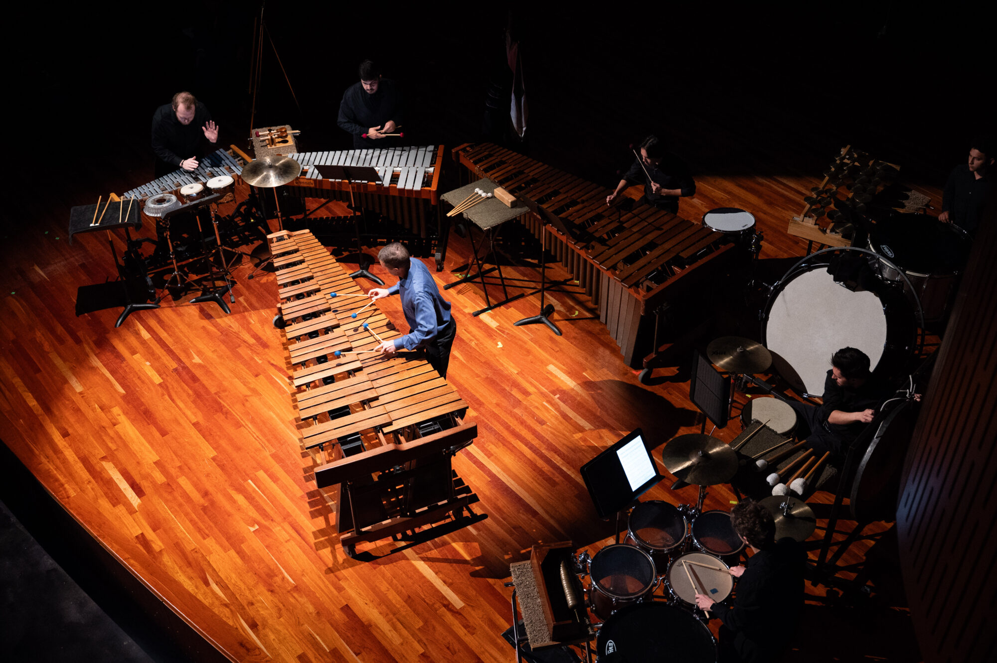 A top-down photo of a percussion ensemble performing on stage.