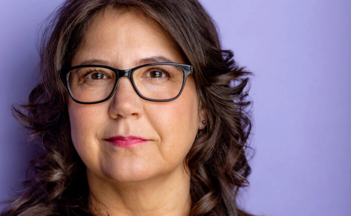 A headshot photo of a person against a lavender background.
