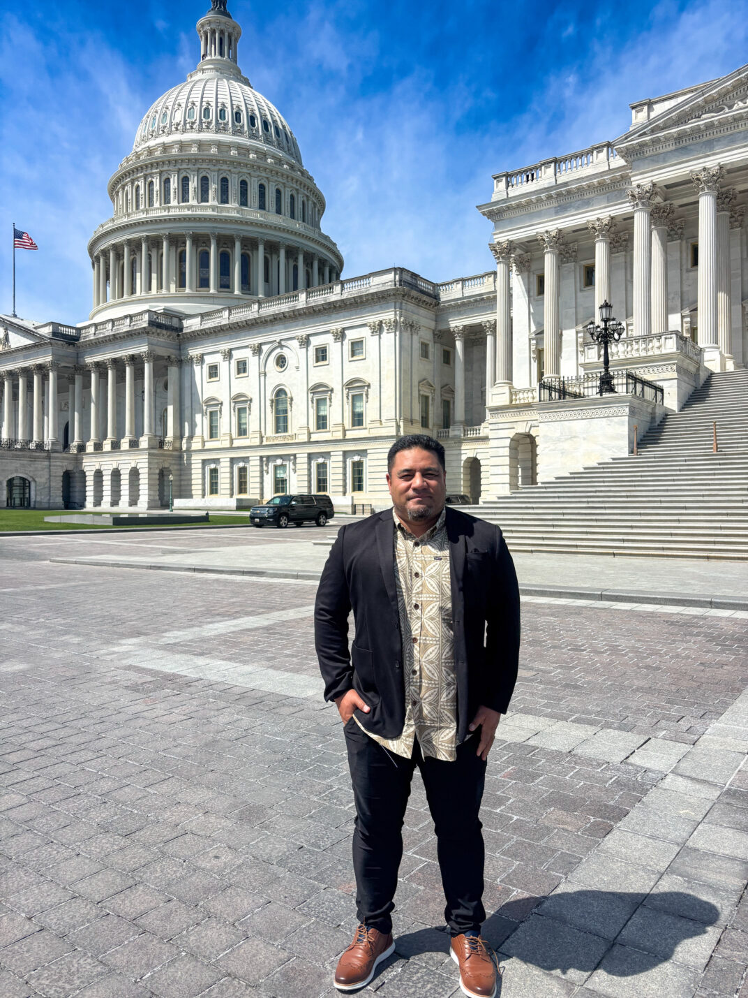 A man standing outside under blue skies in front of the United States Capitol.
