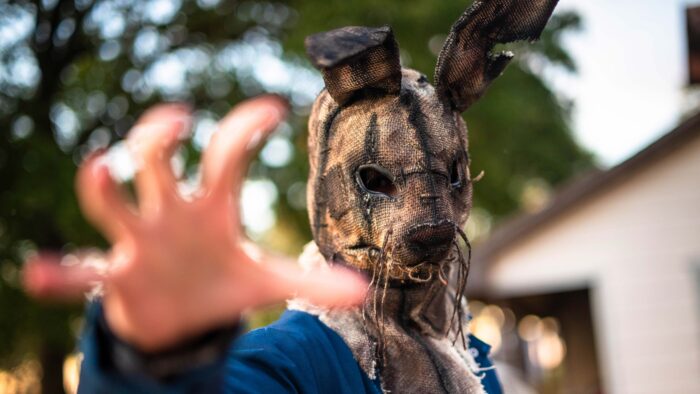 A man with a scary bunny mask holding his hand out toward the camera.