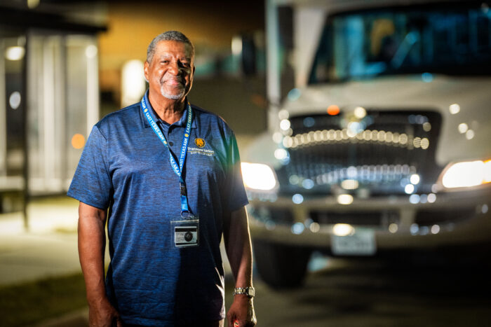 Man standing outside in front of bus, smiling.