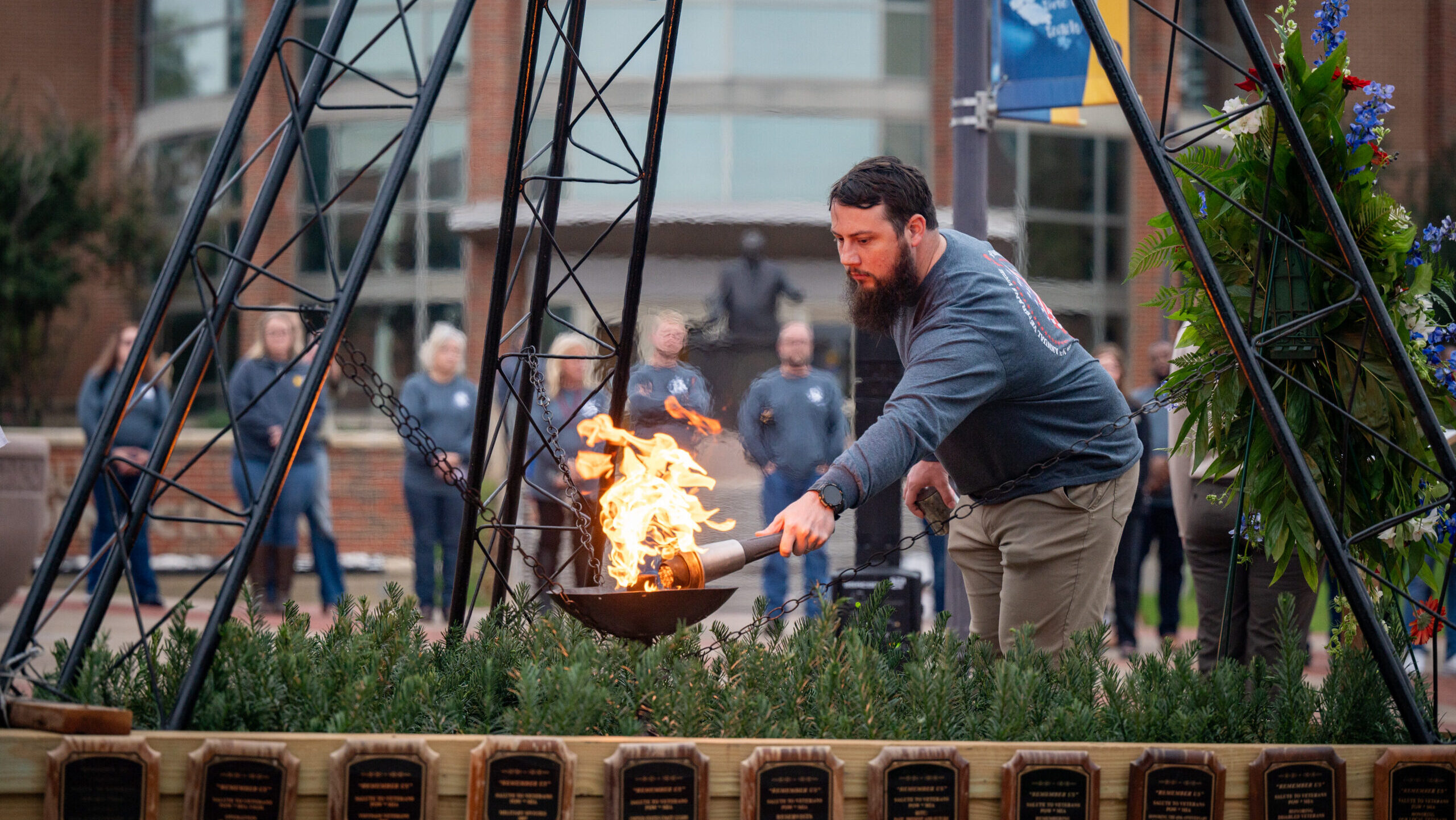 A person using a torch to light a ceremonial flame.