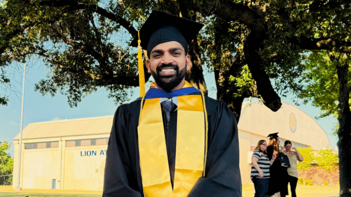 A college graduate in cap and gown posing for a photo.