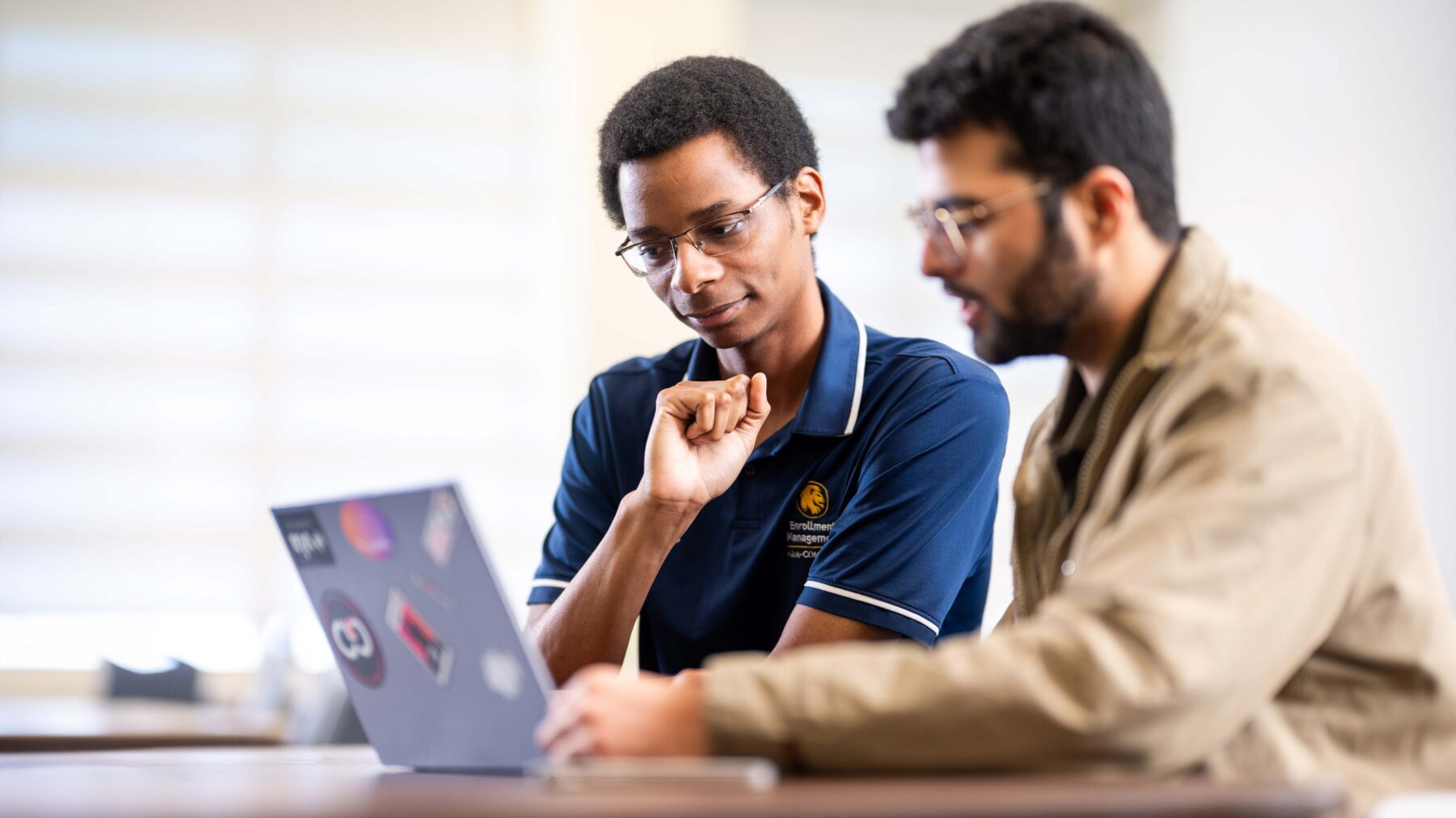 decorative use. Two students look at a laptop.