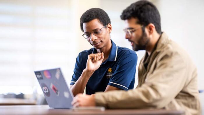 Two people are looking at a laptop screen.