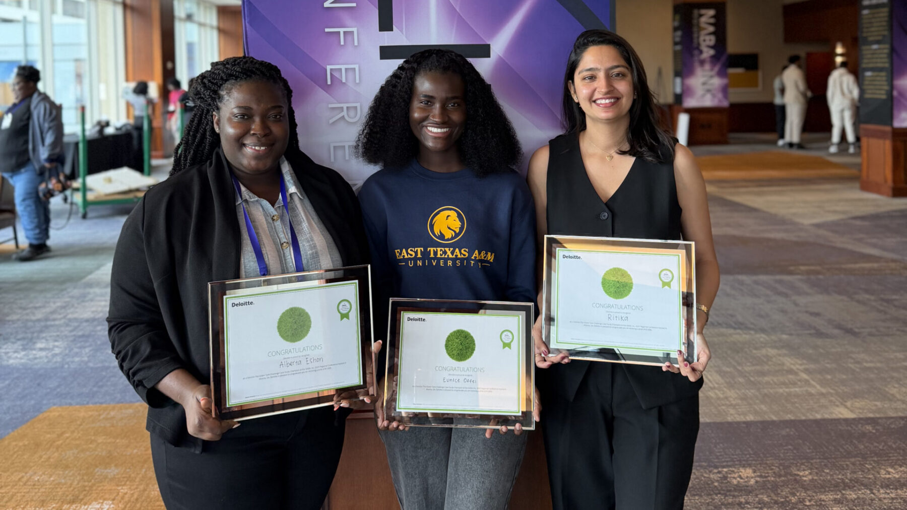 Three people posing with award certificates