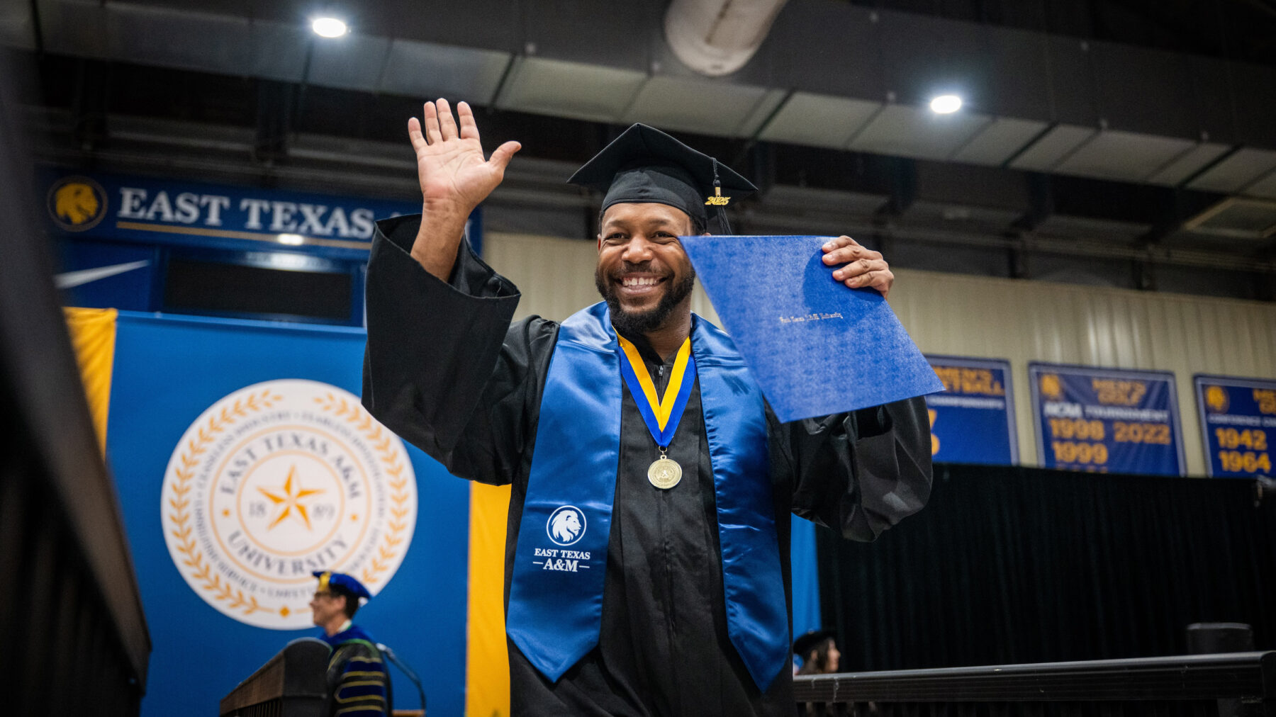 A college graduate smiling with their degree during a graduation ceremony.