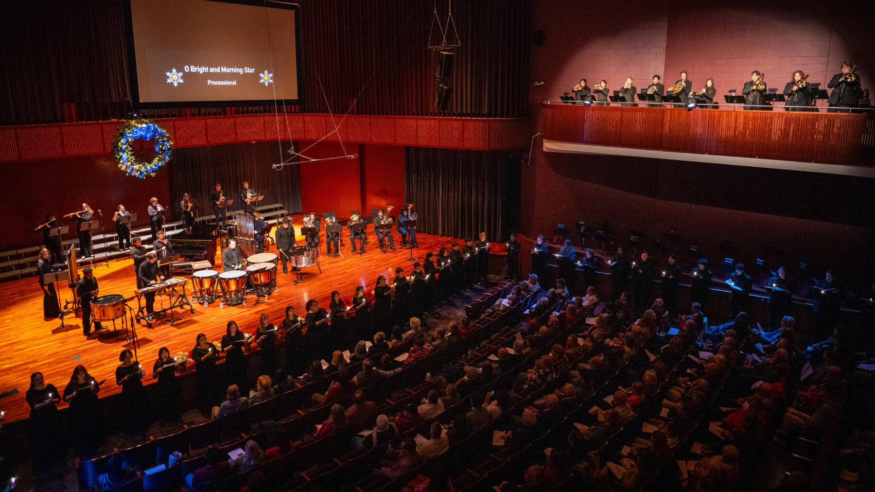 A full concert hall with a vocal and band ensemble performing.
